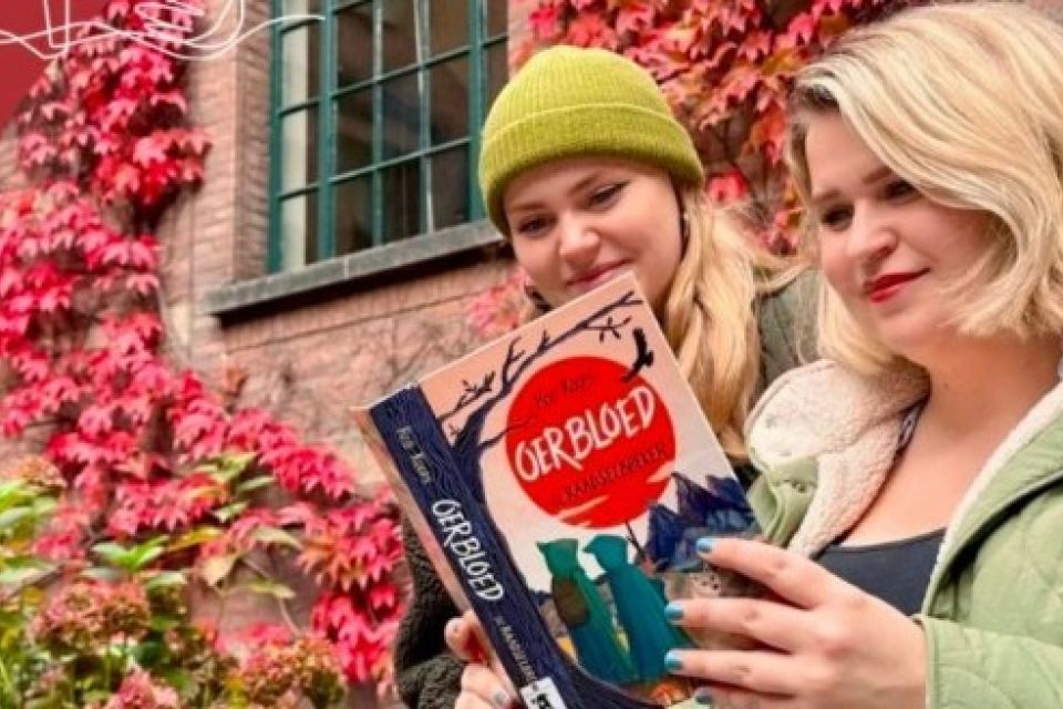 Twee jonge vrouwen lezen samen het boek Oerbloed