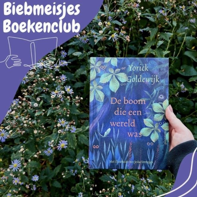 Een hand houdt het boek De boom die een wereld was omhoog. Op de achtergrond planten met paarse bloemen. 